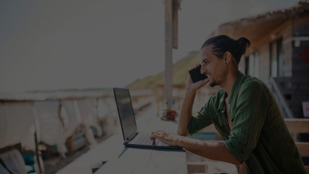 A photo with the text title “Rainmaker Consulting: The Rise of the Digital Nomad Workforce For Business Internationalization,” and a background of a person utilizing a laptop and in a phone call.