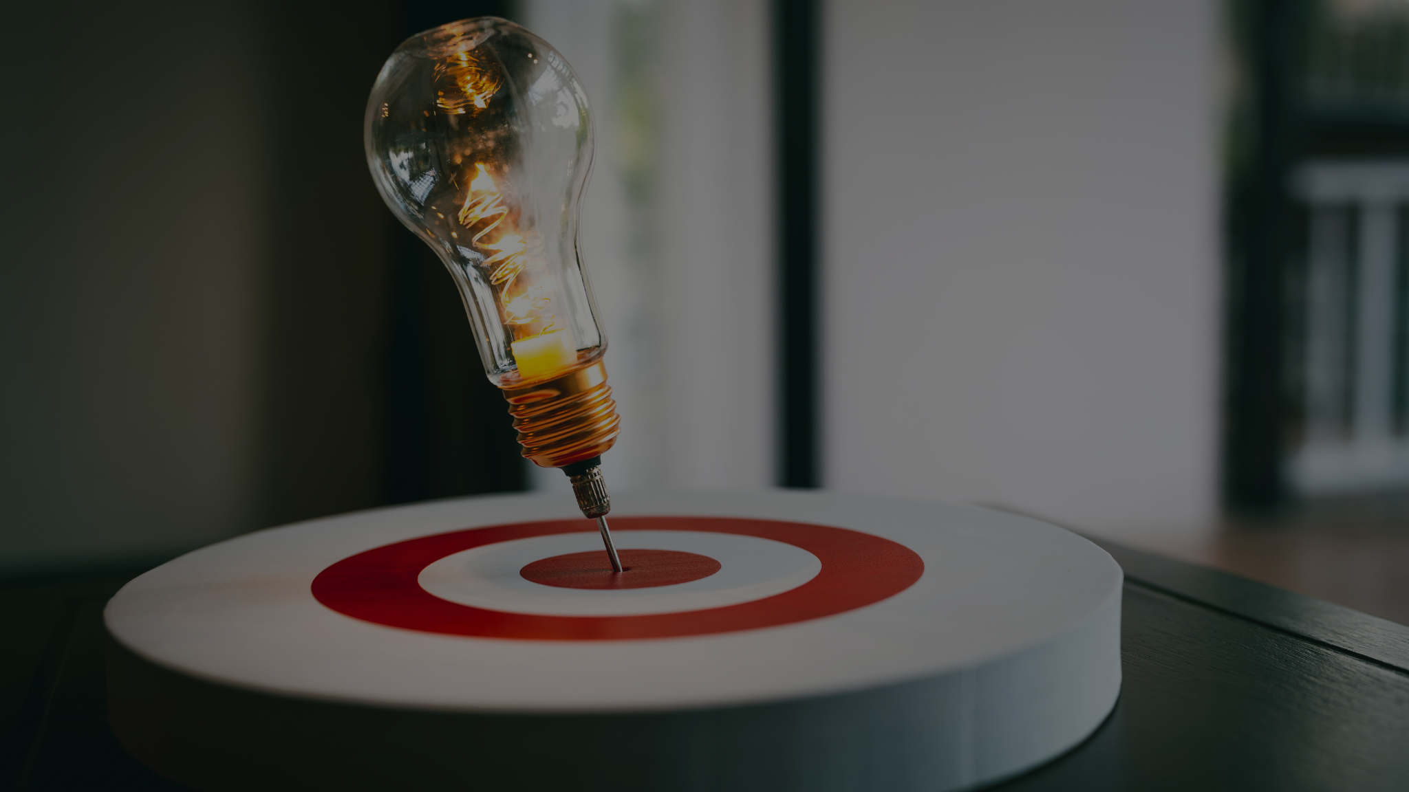 A glowing lightbulb piercing the center of a red-and-white target, symbolizing innovation, precision, and focus in market development insights.